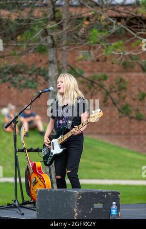 Melanie Morris, guitariste basse du groupe de rock Attaboy, joue et chante lors d'un concert en plein air en Angola, Indiana, États-Unis. Banque D'Images