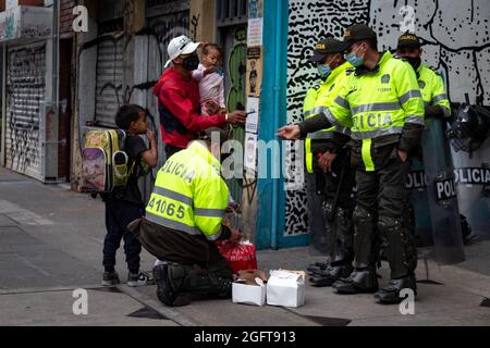 Des policiers ont remis des déjeuners à une famille de migrants vénézuéliens lors d'un rassemblement organisé par des étudiants de l'Universidad Distital, après quelques jours de retour Esteban Mosquera, un dirigeant social et membre de la communauté a été tué deux ans après avoir perdu l'œil sur un cas de brutalité policière, à Bogota, Colombie le 26 août 2021. Banque D'Images