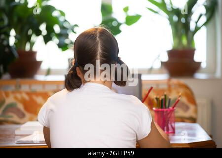 Formation à distance-formation en ligne. Fille d'école regardant des cours d'éducation en ligne et faisant des devoirs d'école. La pandémie COVID-19 force les enfants en ligne Banque D'Images