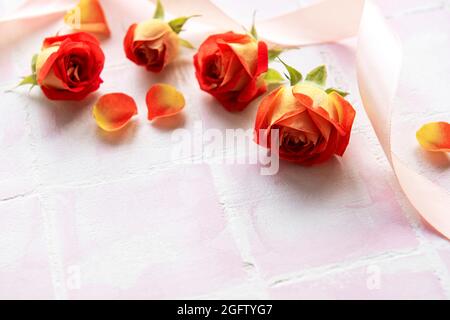 Composition des fleurs. Cadre en roses rouges et pétales sur fond de carreaux roses. Vue de dessus, plat, espace de copie Banque D'Images