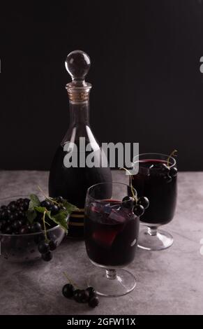 Liqueur de cassis maison dans un verre et décanter sur fond sombre. Banque D'Images