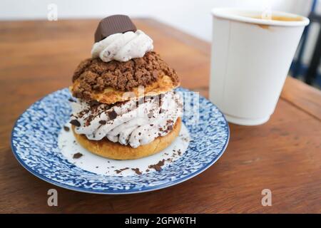 petit pain, pâte de choux avec garniture en poudre de chocolat ou eclair et café chaud pour servir Banque D'Images