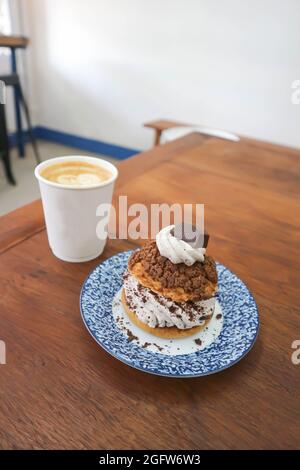 petit pain, pâte de choux avec garniture en poudre de chocolat ou eclair et café chaud pour servir Banque D'Images