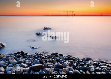 Vue depuis Arbon sur le lac de Constance au lever du soleil avec pierres en premier plan, en Suisse Banque D'Images