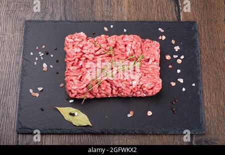 Viande hachée avec une branche de graines de carvi et d'épices sur un panneau en pierre d'ardoise noire. Vue de dessus. Banque D'Images