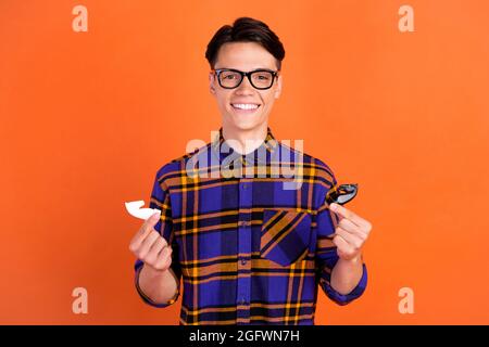 Photo de millenny drôle gars jouer tenue d'échecs vêtements de chemise à carreaux lunettes isolées sur fond de couleur orange Banque D'Images