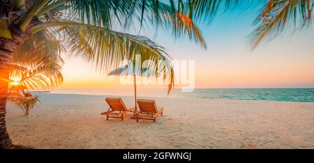 Magnifique coucher de soleil tropical pittoresque, deux chaises longues, parasols feuilles de palmier.Horizon de l'île en bord de mer, ciel romantique au crépuscule.Vacances Banque D'Images