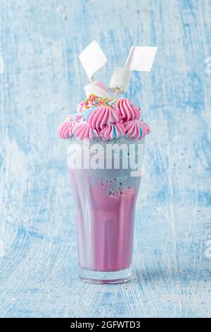 Milkshake bleu et rose décoré de guimauves sur fond bleu. Banque D'Images