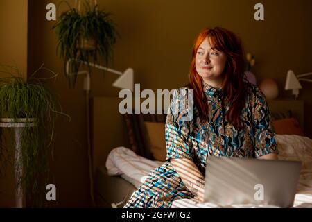 Femme au lit qui regarde loin Banque D'Images