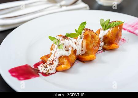 Plat traditionnel russe de pelmeni, boulettes russes avec sauce tomate et yaourt Banque D'Images