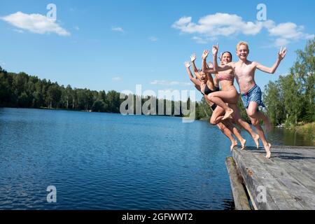 Jeunes amis qui sautent dans le lac Banque D'Images