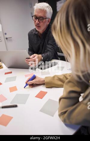 Les professionnels utilisent des notes adhésives et un ordinateur portable au bureau Banque D'Images