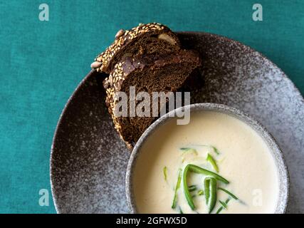 Bol en argile de soupe à la crème de saumon finlandaise servi avec du poireau et des croûtons sur fond vert de nappe. Concept d'alimentation saine. Arrière-plan alimentaire avec espace de copie. Gros plan, mise au point sélective. Banque D'Images