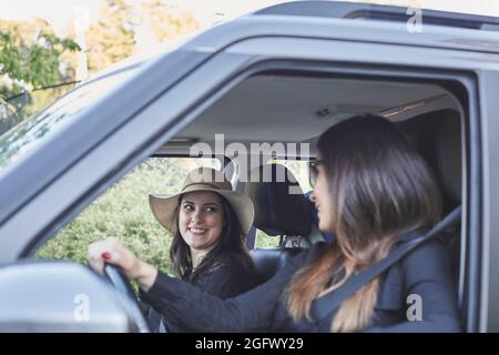 Femmes souriantes assises en voiture Banque D'Images