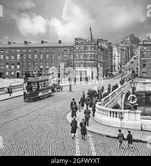 Vue du début du XXe siècle sur un tramway électrique traversant le pont Patrick au-dessus de la rivière Lee à Cork, en Irlande. Le premier pont, achevé en 1789 et incorporant un portcullis pour réglementer le trafic maritime sous le pont, a été détruit par une grave inondation en 1853. Un pont temporaire en bois, a été mis en place et le pont actuel a ouvert en 1861, reste l'un des plus célèbres monuments de Cork. Banque D'Images