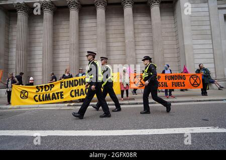 Des policiers de la ville de Londres marchent devant des manifestants lors d'une manifestation par des membres de la rébellion d'extinction à la Banque d'Angleterre, dans la ville de Londres. Date de la photo : vendredi 27 août 2021. Banque D'Images