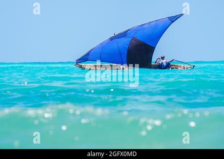 Pêcheur naviguant en canoë avec voile bleu. Zanzibar, Tanzanie, Afrique Banque D'Images