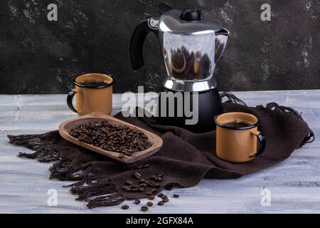 Cafetière italienne et deux tasses à café avec grains de café rôtis dans un récipient en bois Banque D'Images