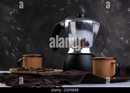 Cafetière italienne et deux tasses à café avec grains de café rôtis dans un récipient en bois Banque D'Images