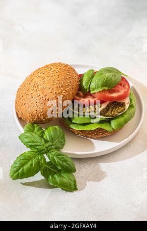 Sandwich au Caprese avec tomates fraîches, mozzarella, pesto et feuilles de basilic sur une assiette blanche. Une collation saine. Concept d'alimentation saine. Foc sélectif Banque D'Images