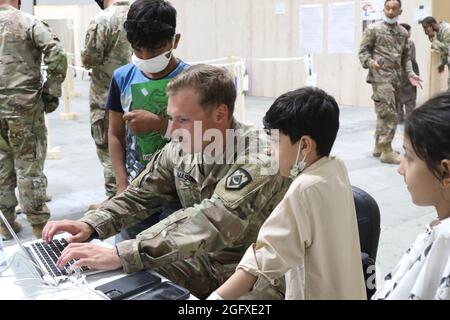 Un soldat de la Garde nationale américaine de la Force opérationnelle Spartan, U.S. Army Central, partage son ordinateur pour divertir les enfants afghans évacués au Camp Buehring, au Koweït, le 25 août 2021. Les soldats de l'USARCENT l'ont frappé rapidement avec les enfants à l'installation, trouvant des moyens d'apporter des sourires et des divertir par le processus d'arrivée. (É.-U. Photo de l'armée par PFC. Katelynn Bissell) Banque D'Images