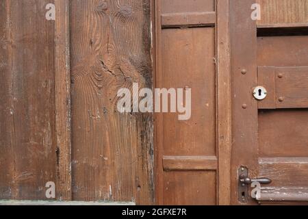 Gros plan de porte marron fermée avec poignée de porte et trou de serrure dans une maison en bois vieillie. Banque D'Images