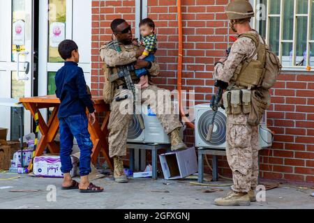 Une marine américaine avec un groupe de travail maritime aérien-terrestre à but spécial - intervention en cas de crise - Commandement central, interagit avec les enfants lors d'une évacuation à l'aéroport international Hamid Karzaï, Kaboul, Afghanistan, août 24. Les membres du service américain aident le ministère d'État à effectuer une opération d'évacuation non combattantes (NEO) en Afghanistan. (É.-U. Photo du corps marin par lance Cpl. Nicholas Guevara) Banque D'Images