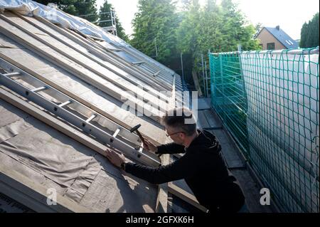 Couvreur fixant une nouvelle isolation sur le toit d'une ancienne maison. Banque D'Images