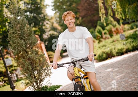 Jeune homme actif appréciant son entraînement à vélo Banque D'Images
