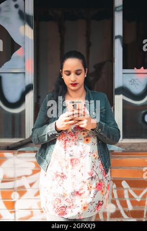 Photo verticale d'un fémal latin vérifiant son téléphone portable Banque D'Images
