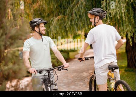 Les cyclistes en casques parlent les uns aux autres dans un parc Banque D'Images