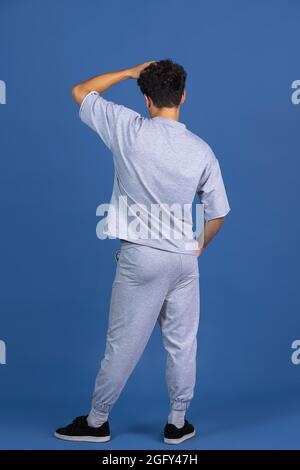 Vue arrière d'un jeune homme mauriquement isolé sur fond bleu, bleu marine studio. CopySpace pour la publicité, la conception. Concept des émotions humaines, de la mode, de la beauté Banque D'Images