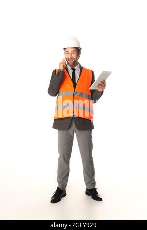 Ingénieur souriant tenant une tablette numérique et parlant sur un smartphone sur fond blanc Banque D'Images