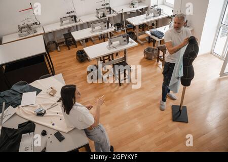 Vue de dessus des designers interraciaux qui parlent près du mannequin dans le studio Banque D'Images