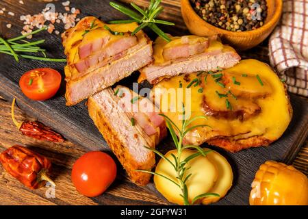 Hacher le porc mariné dans de la sauce moutarde avec du bacon et du fromage. Viande grillée au fromage. Portions de viande sur la table. Banque D'Images