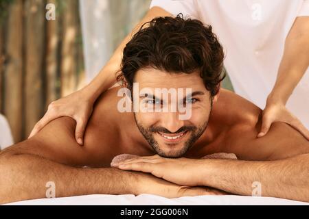 Massage thaïlandais. Portrait de l'homme beau pendant un massage des épaules et du dos avec des mains masseuses au centre de bien-être Banque D'Images