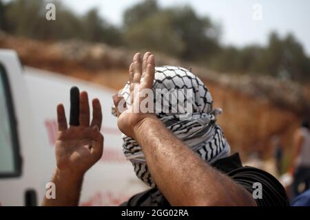 Naplouse, Cisjordanie, Palestine. 24 août 2021. Un palestinien masqué prend couvert de gaz lacrymogène lors de la manifestation contre l'avant-poste israélien d'Eviatar dans le village de Beita près de la ville de Naplouse en Cisjordanie. (Credit image: © Nasser Ishtayeh/SOPA Images via ZUMA Press Wire) Banque D'Images