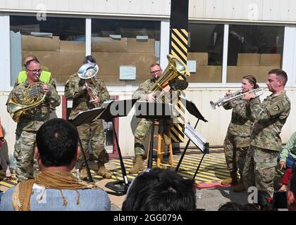 Ramstein Miesenbach, Allemagne. 24 août 2021. Les réfugiés afghans écoutent la bande Europe et Afrique de l'armée américaine qui joue de la musique dans le camp de réfugiés de la base aérienne de Ramstein le 22 août 2021 à Ramstein-Miesenbach, en Allemagne. La base aérienne de Ramstein fournit un hébergement temporaire aux personnes évacuées d'Afghanistan dans le cadre de l'opération alliés refuge. Credit: Planetpix/Alamy Live News Banque D'Images