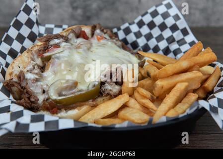 Sandwich au cheesesteak Philly ouvert, fumé dans du fromage à la moelette, servi avec des frites de steak pour un repas appétissant. Banque D'Images