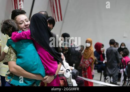 Un soldat central de l'armée américaine accueille des jeunes filles évacuées afghanes avec des hugs pendant le processus d'arrivée au Camp Buehring, au Koweït, le 25 août 2021. Les soldats de l'USARCENT l'ont frappé rapidement avec les enfants à l'installation, trouvant des moyens d'apporter des sourires et des rires à travers le processus. (É.-U. Photo de l'armée par le Sgt. Marc Loi) Banque D'Images