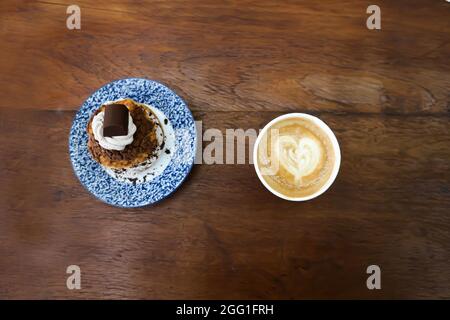 petit pain, pâte de choux avec garniture en poudre de chocolat ou eclair et café chaud pour servir Banque D'Images