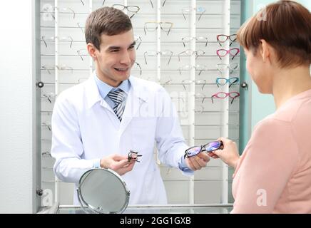 Jeune médecin d'aider une femme à choisir de nouvelles lunettes en boutique