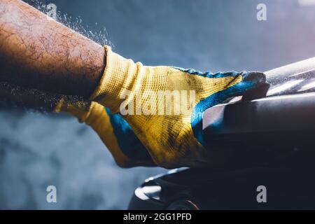 Le technicien tire manuellement le capot de la voiture pour l'entretien dans le garage de réparation Banque D'Images
