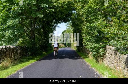 Cycliste mâle sur la voie tranquille de Harrop Fold de Holden, Bowland, Lancashire, Royaume-Uni. Banque D'Images