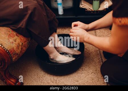 Homme thaïlandais se lavant les jambes et faisant un massage thaï classique procédure à la jeune femme au salon de beauté spa Banque D'Images