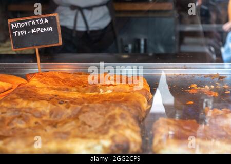 Bougatsa, pâtisserie à la crème ou au fromage dans un magasin, cuisine de rue. Étiquette avec texte en grec. Petit-déjeuner traditionnel avec des mets sucrés ou salés Banque D'Images