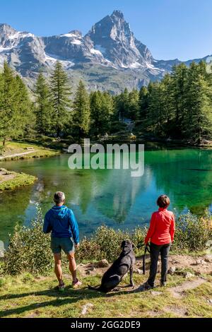 Un couple avec un chien admire le magnifique paysage de Lago Blu ou Layet, qui reflète le Mont Cervino, Vallée d'Aoste, Italie Banque D'Images