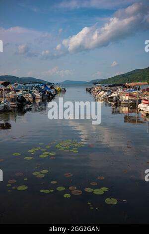 Cooperstown, NY, USA - 11 août 2021 : les eaux bleues du lac Otsego lors d'une journée ensoleillée d'été, reflètent les cumulus près d'un quai avec de l'eau de loisirs Banque D'Images