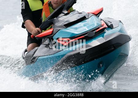 Hel, Pologne - 08.01.2021: Gros plan frontal de l'homme et du garçon dans la vie gilets de conduite rapide sur un scooter des eaux avec beaucoup de gouttelettes volantes à travers le Banque D'Images