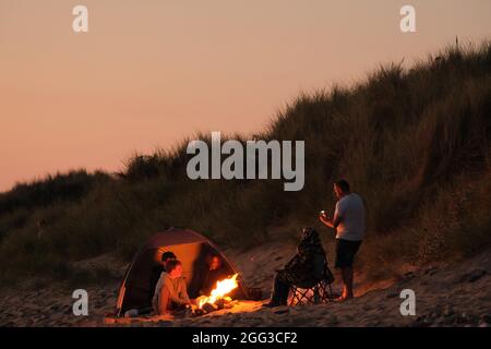 Feux de camp d'été sur la plage de Llangennith, péninsule de Gower, près de Swansea, Royaume-Uni. Remarque : les images peuvent présenter une légère douceur et un certain bruit de signal, tel qu'il est pris avec des paramètres ISO très élevés. Ne convient pas à une reproduction plus large. Banque D'Images